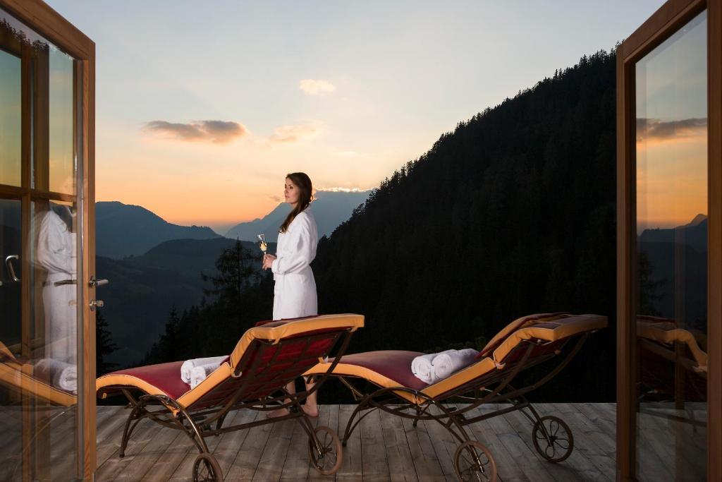 Eine Frau steht auf einem Balkon mit zwei Stühlen in der Unterkunft Romantiksuite in Alpbach