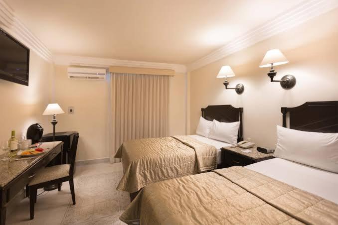 a hotel room with two beds and a desk at Casa palmar sercas del Nilo in Mexico City