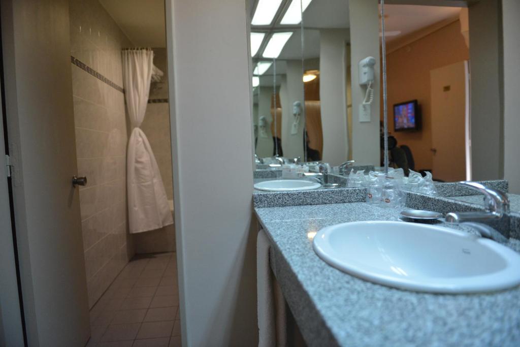 a bathroom with two sinks and a shower at Comodoro Hotel in Comodoro Rivadavia
