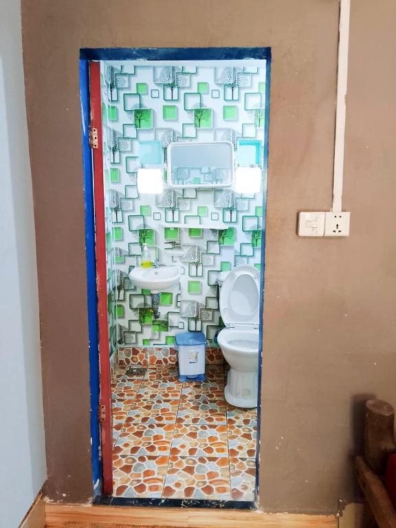 a bathroom with a toilet and a tile wall at Lazy Bones in Koh Rong Sanloem