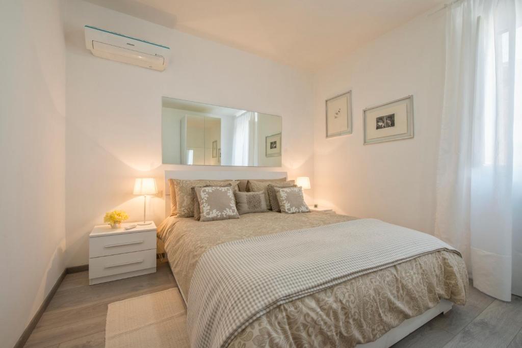 ein weißes Schlafzimmer mit einem Bett und einem Spiegel in der Unterkunft Vatican Holiday Apartment 317 in Rom