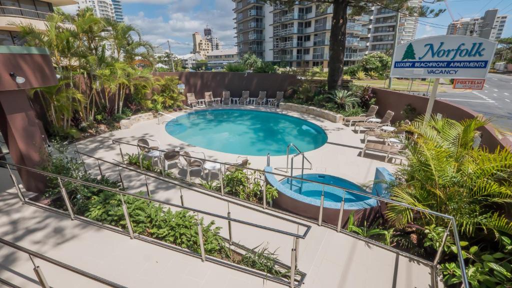 a patio area with chairs, tables, and umbrellas at Norfolk Luxury Beachfront Apartments in Gold Coast