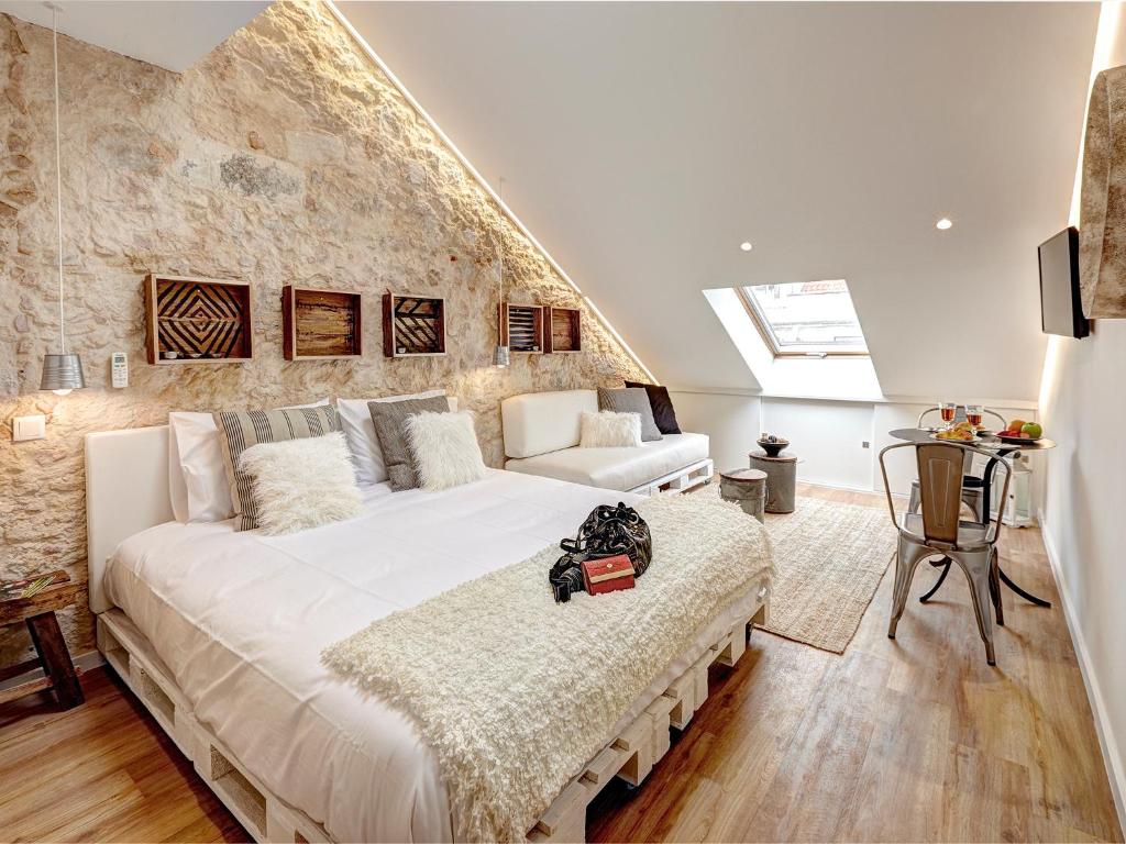 una camera da letto con un grande letto bianco e un muro di pietra di Sonel Investe Madalena 287 Boutique Apartments by Get Your Stay a Lisbona