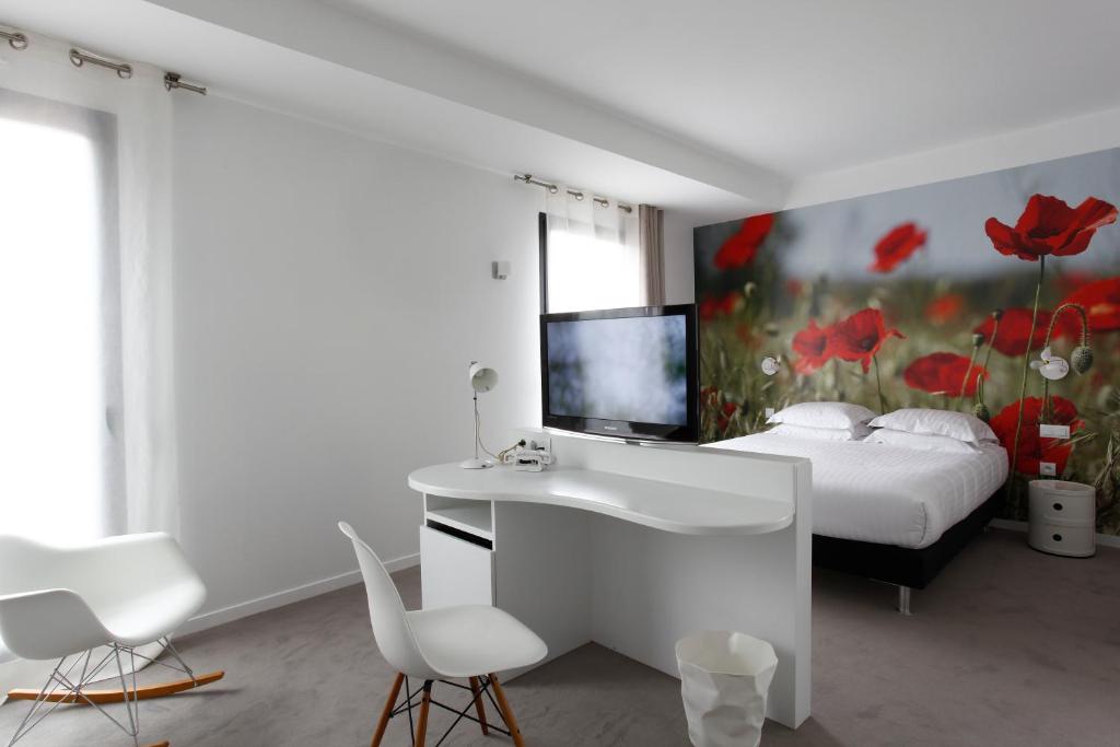 a white bedroom with a bed and a desk and chairs at L’Échappée Belle in LʼIsle-Jourdain