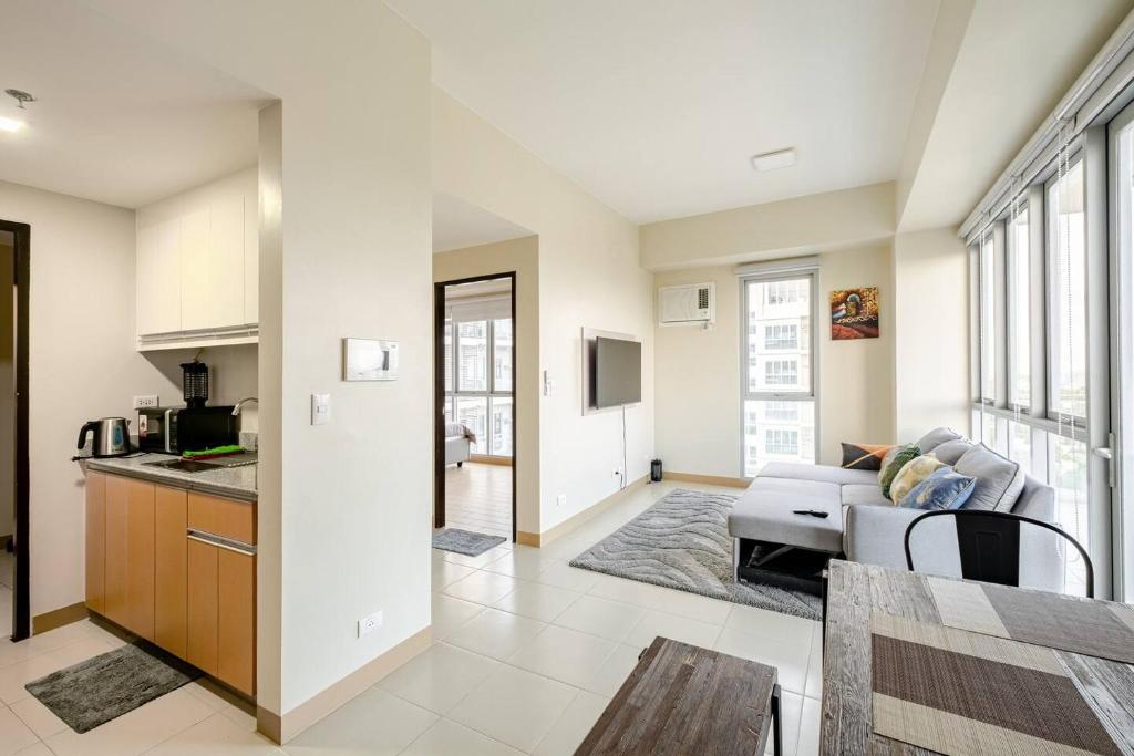a kitchen and a living room with a couch at Luxury Corner Suite 1 Bedroom plus Den Top Floor Birds Eye View Spacious 668 square Feet in Iloilo City