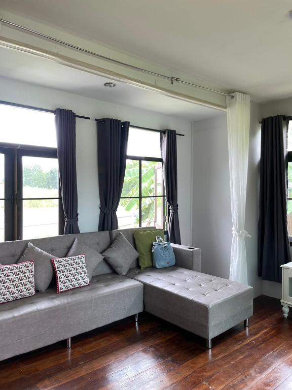 a living room with a gray couch and windows at Pool Dara Resort in Hua Hin