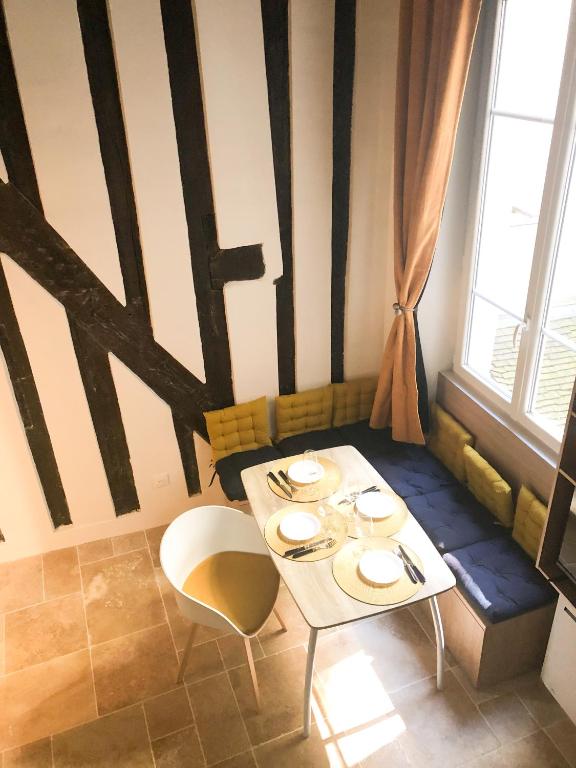 une table et des chaises dans une pièce avec une fenêtre dans l'établissement Quartier d'Emily in Paris, à Paris