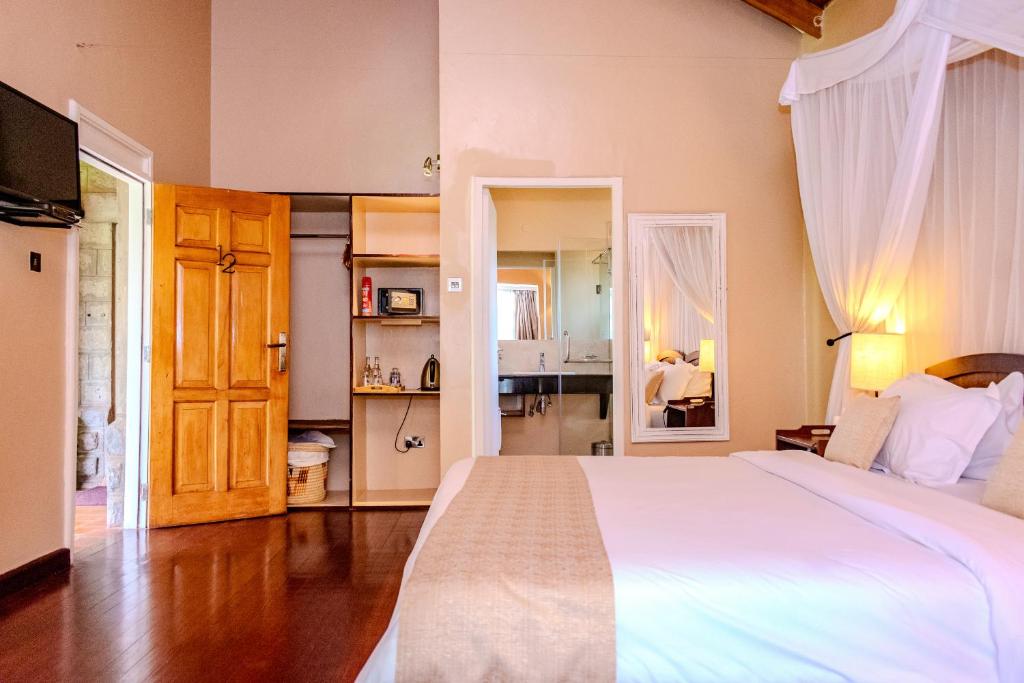 a bedroom with a large white bed and a kitchen at Aero Club of East Africa in Nairobi