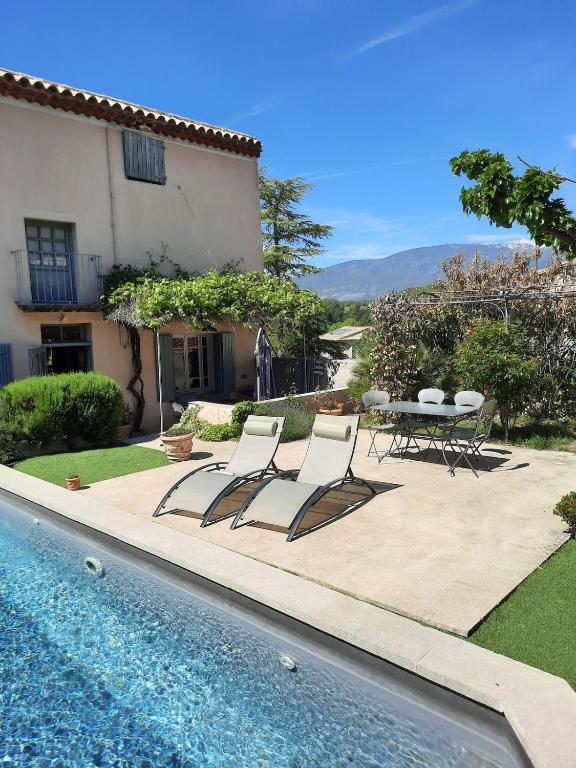 un patio avec une table et des chaises à côté d'une piscine dans l'établissement Maison familiale sur la route du Ventoux, à Mormoiron