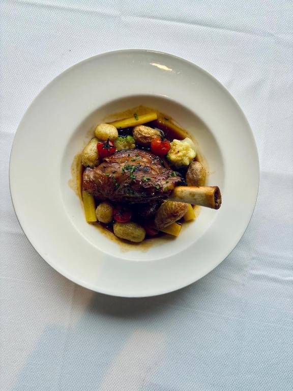 a plate of food with meat and vegetables on a table at La Cremaillere Hôtel-Restaurant in Courseulles-sur-Mer