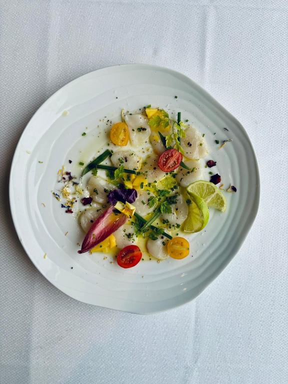 a white plate of food with vegetables on a table at La Cremaillere Hôtel-Restaurant in Courseulles-sur-Mer