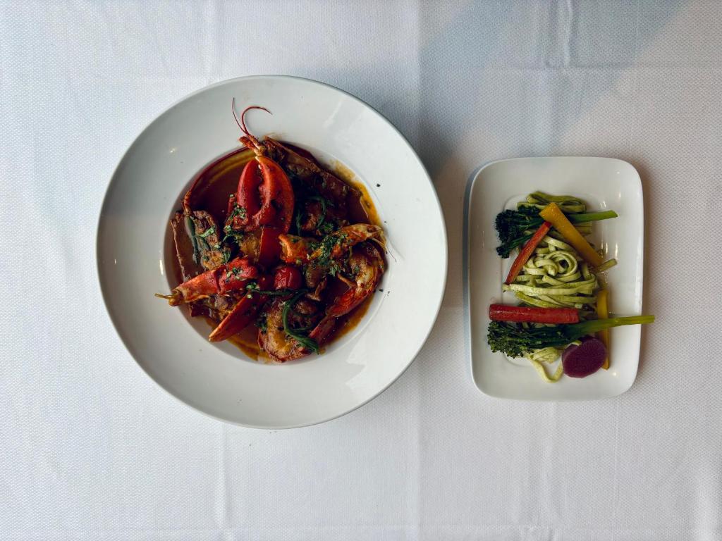 a plate of food and a plate of vegetables on a table at La Cremaillere Hôtel-Restaurant in Courseulles-sur-Mer
