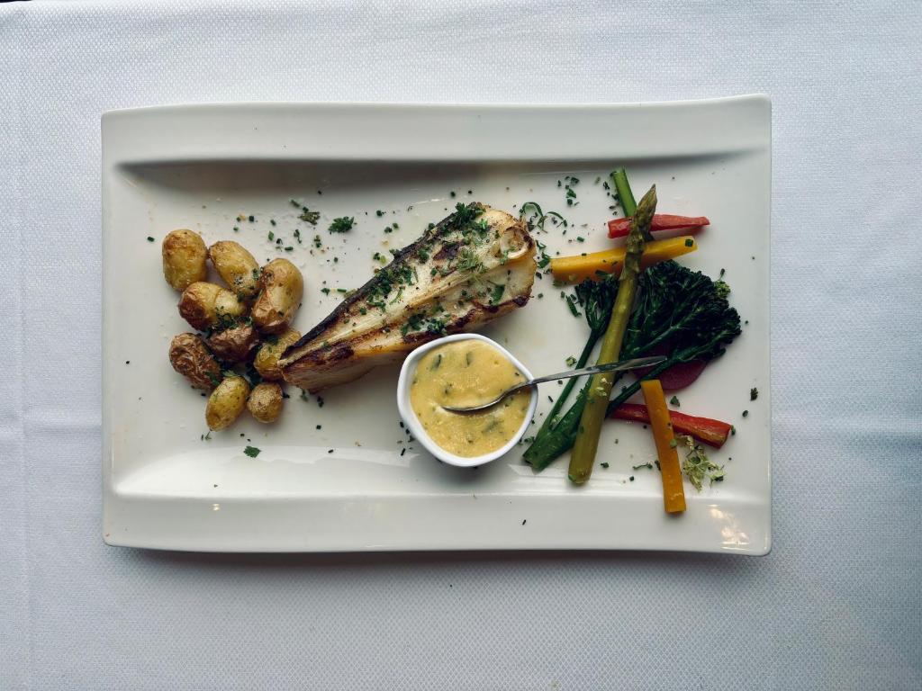 a plate of food with fish and vegetables on a table at La Cremaillere Hôtel-Restaurant in Courseulles-sur-Mer