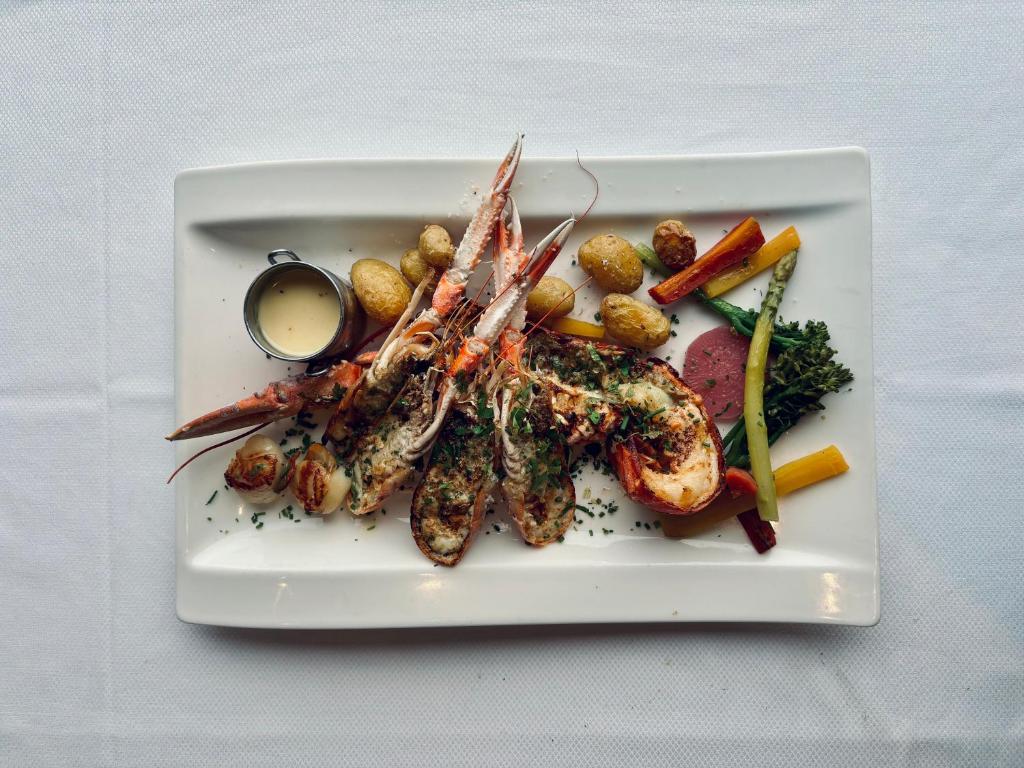 a plate of food with seafood and vegetables on a table at La Cremaillere Hôtel-Restaurant in Courseulles-sur-Mer