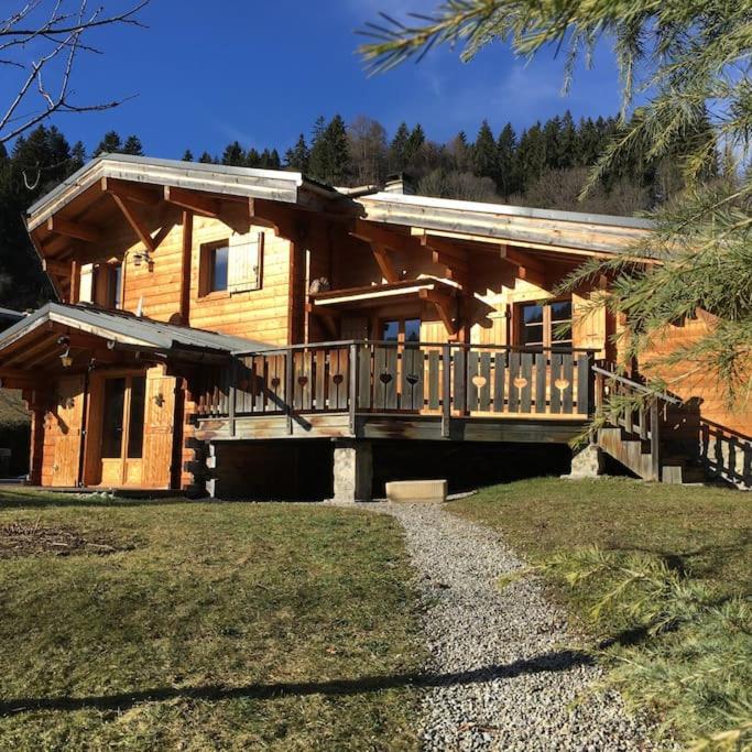 une cabane en rondins avec une terrasse couverte et une maison dans l'établissement Chalet vue montagne , proche des pistes, à Megève