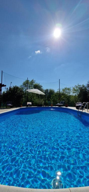 een groot blauw zwembad met daarboven de zon bij Villa Bistre in Radovin