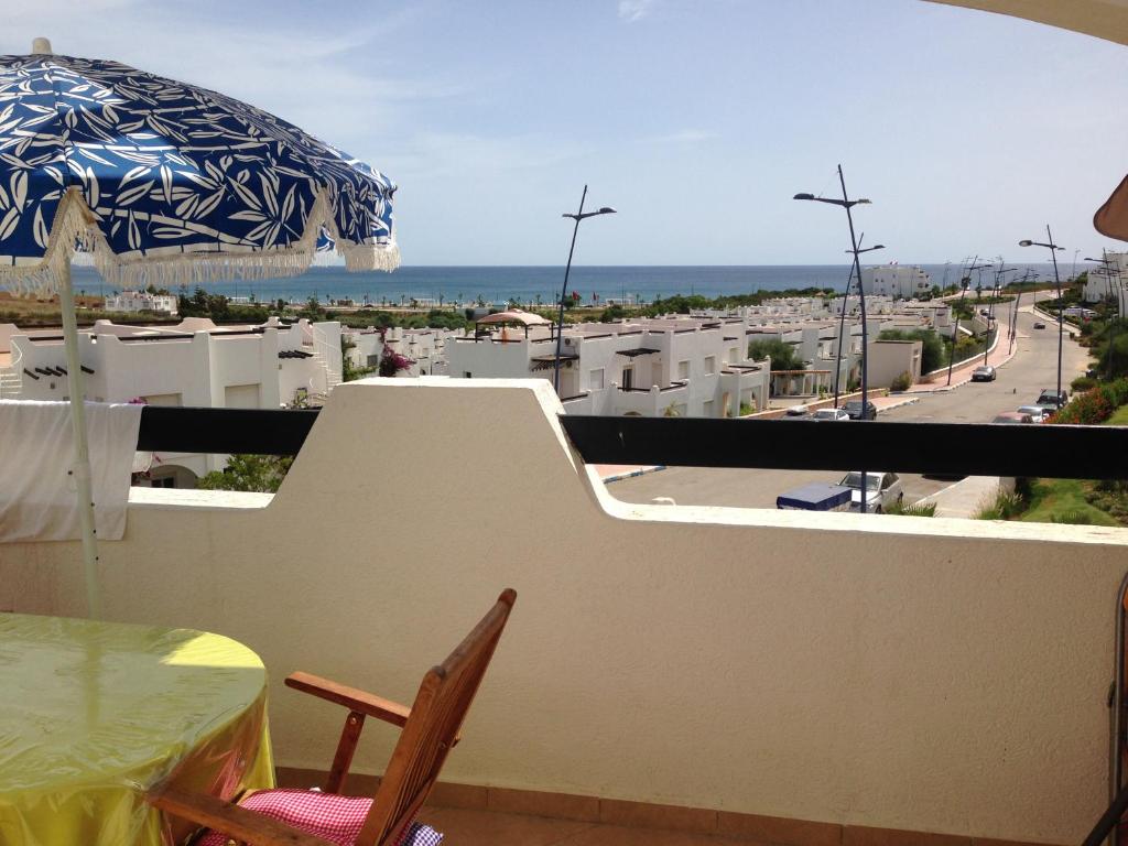 uma varanda com uma mesa e um guarda-chuva em Alcudia Smir em Fnideq