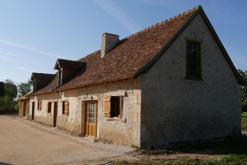 an old stone building with a brown roof at Le Coin des Hortensias in La Puye