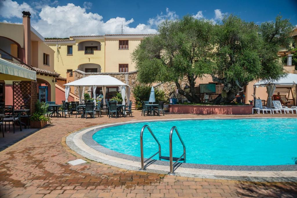 a swimming pool with tables and chairs next to a building at Li Troni in Budoni