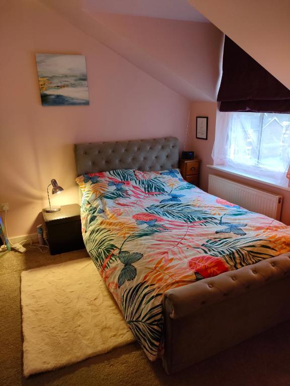 a bedroom with a bed with a colorful comforter at Cosy flat in central Wellington in Telford