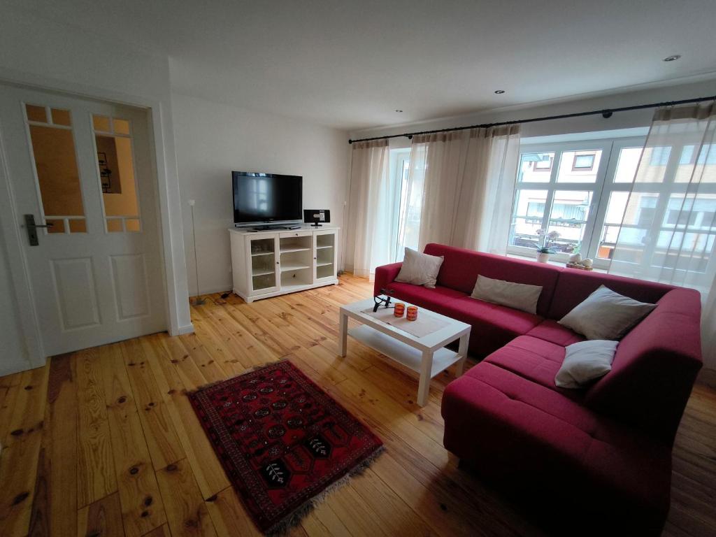 Una sala de estar con un sofá rojo y un televisor. en Haus Rosalinde, en Klüsserath
