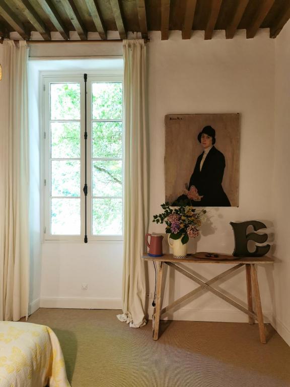 a bedroom with a painting of a woman on a table at La manufacture royale de la bonde Chambre 1 in Cuxac-Cabardès