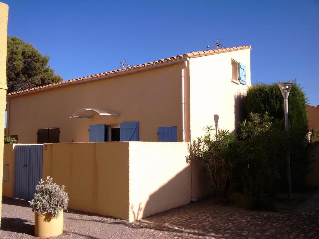 une maison blanche avec une clôture devant dans l'établissement Au calme, à 400m de la mer, au Barcarès