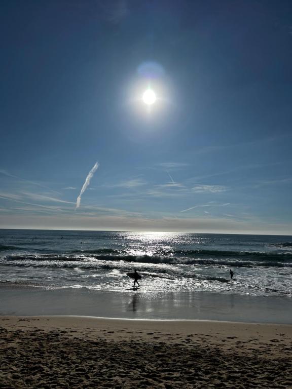 una persona caminando por la playa con una tabla de surf en Blue Chill Carcavelos, en Carcavelos
