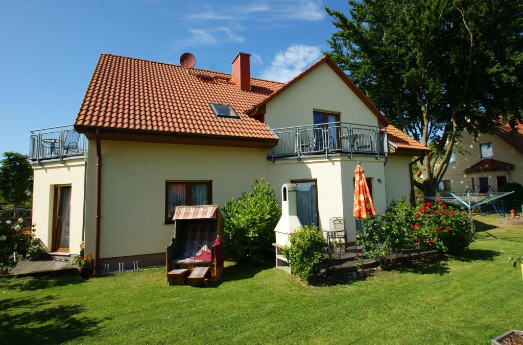 ein kleines weißes Haus mit einem Hof mit Rasen sidx sidx sidx in der Unterkunft Ferienwohnung Koserow in Ostseebad Koserow