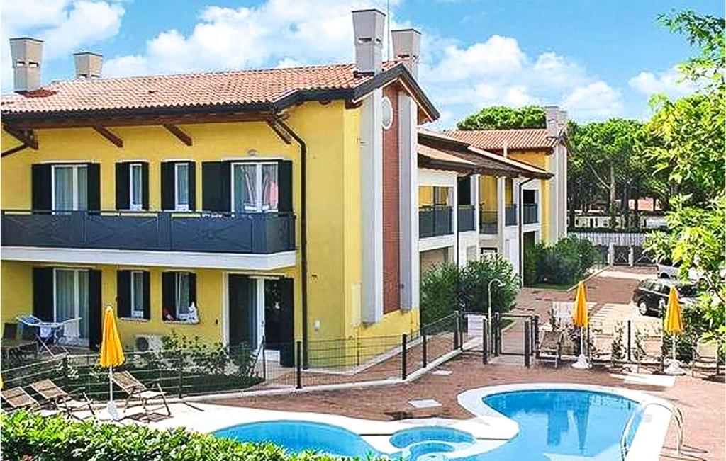 ein gelbes Haus mit einem Pool davor in der Unterkunft Cozy Apartment In Cavallino-Treporti in Cavallino-Treporti