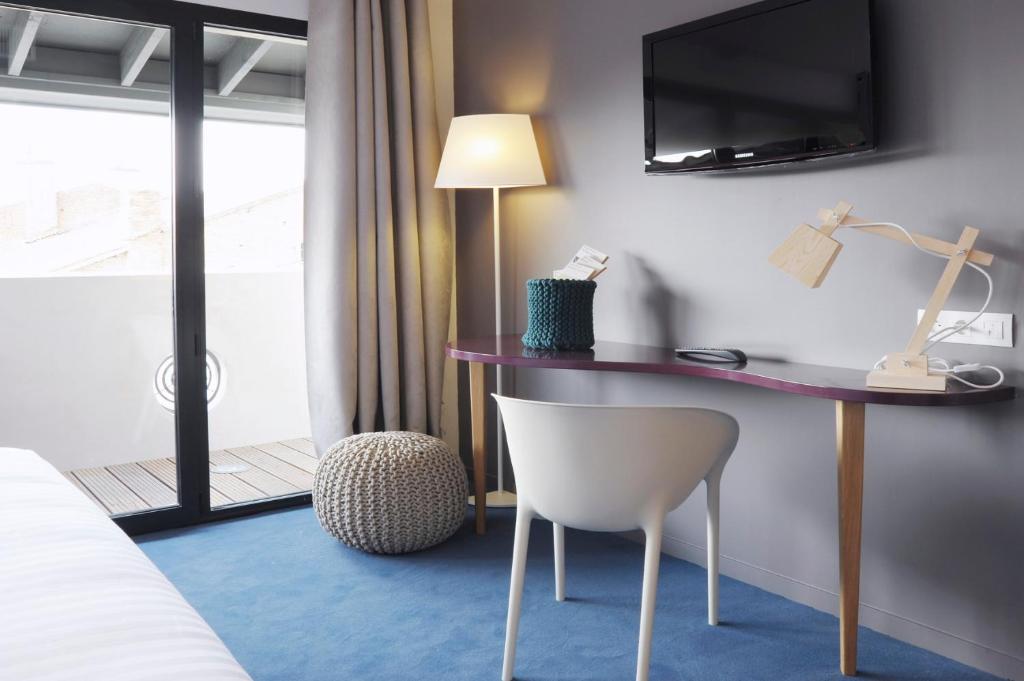 a hotel room with a desk and a chair at L’Échappée Belle in LʼIsle-Jourdain