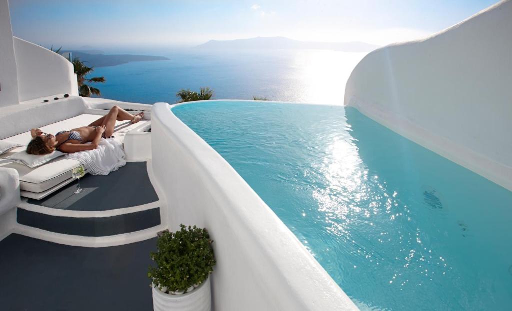 a large pool with a balcony overlooking the ocean at Dana Villas & Infinity Suites in Firostefani