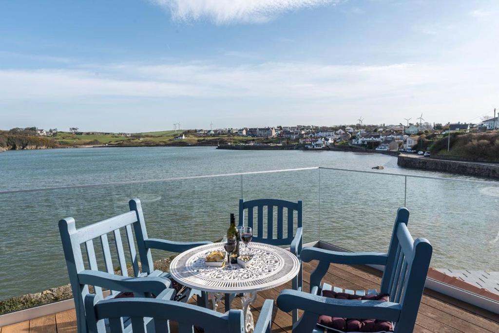 une table et des chaises sur un balcon avec vue sur l'eau dans l'établissement The View at The Moorings, à Baie de Cemaes