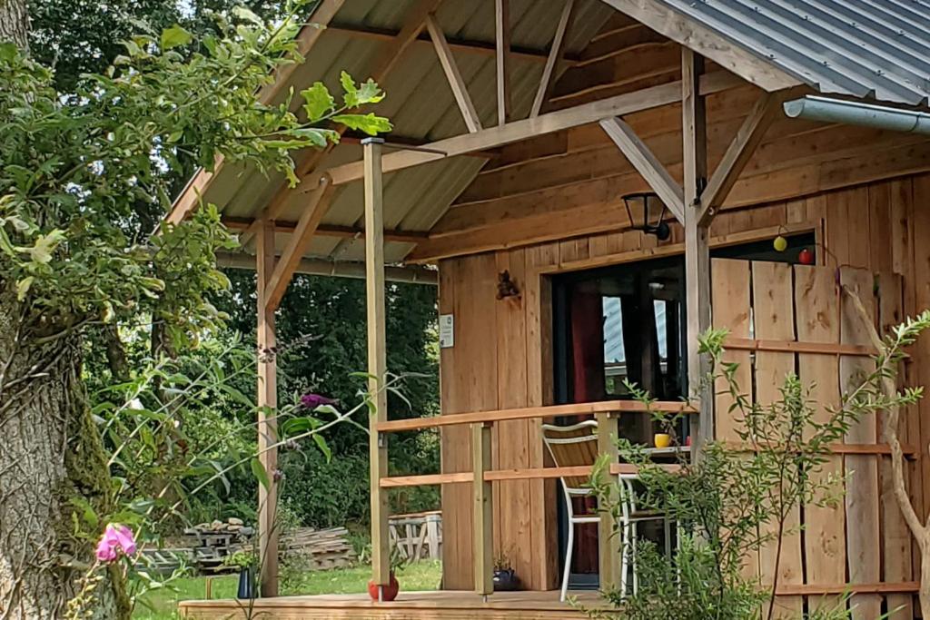Ce chalet en bois dispose d'une véranda et d'une porte. dans l'établissement Le Chat qui pêche, maisonnette en bois, Les Kabanes en Kreiz Breizh, à Rostrenen