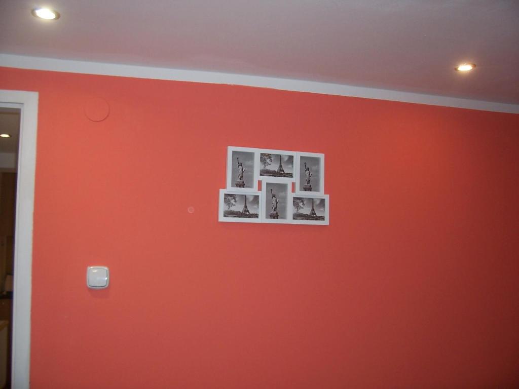 a red wall with three pictures on it at Triton Apartment Budapest in Budapest