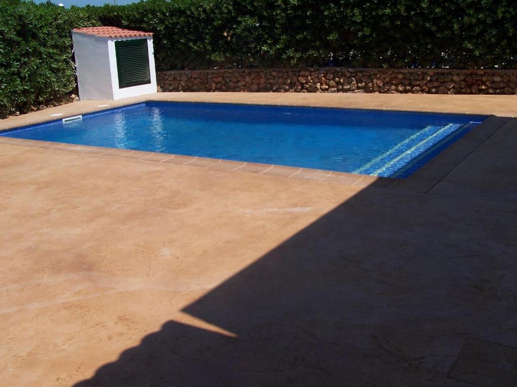 a swimming pool in a yard with a shadow on the ground at Illa Colom in Cala en Bosc