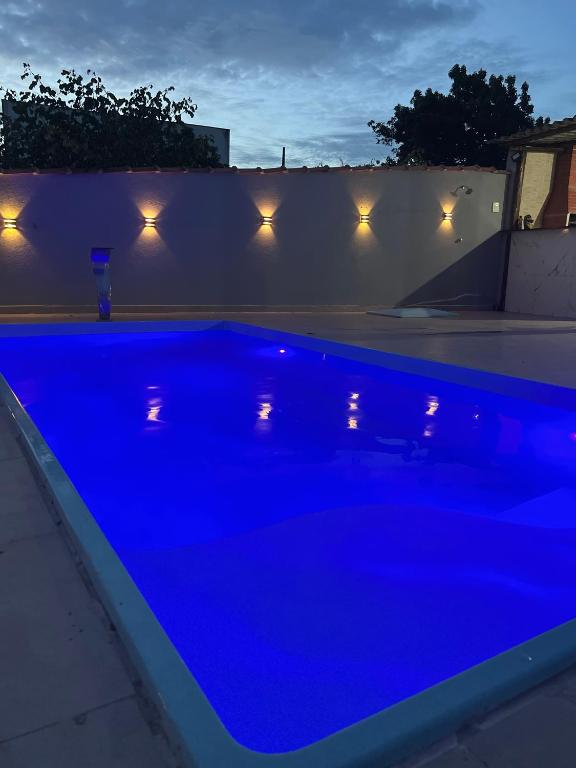 a blue swimming pool in a backyard at night at Casa temporada Guarapari in Guarapari