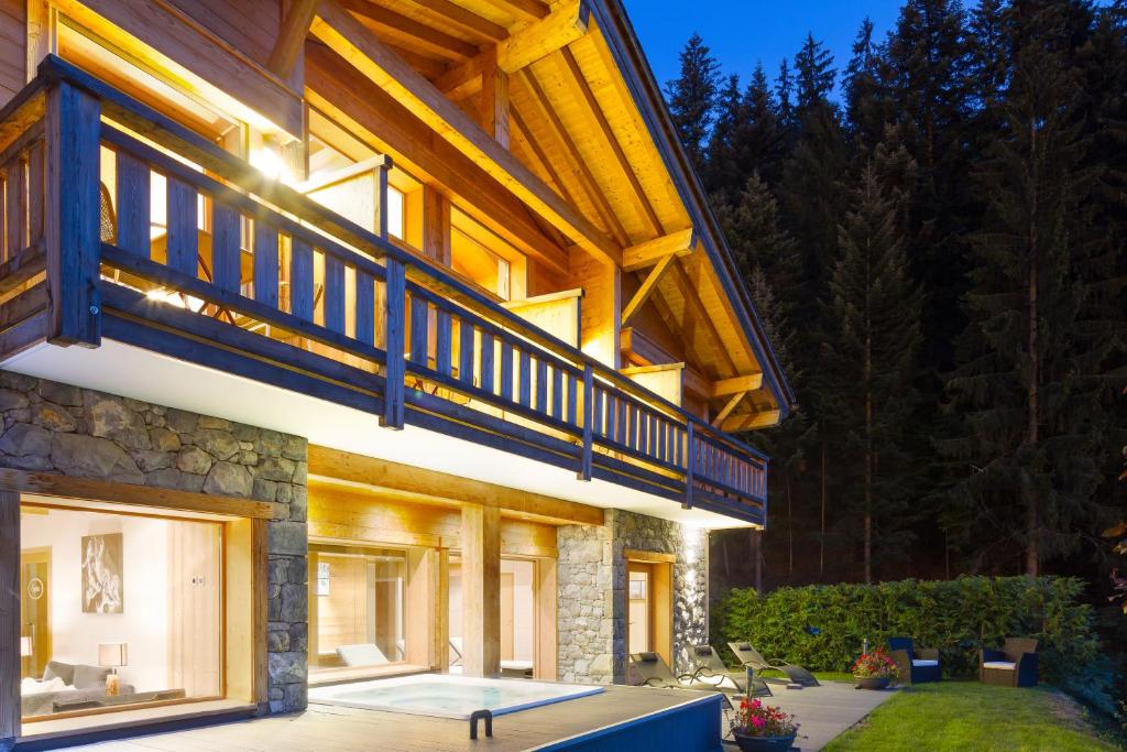 uma grande casa com um deque e um pátio em Chalet-Hotel et Spa Le Delta em Le Grand-Bornand