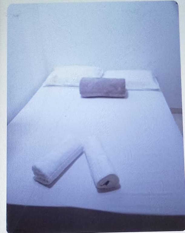 een wit bed met een handtas erop bij Alugo quarto in Penha