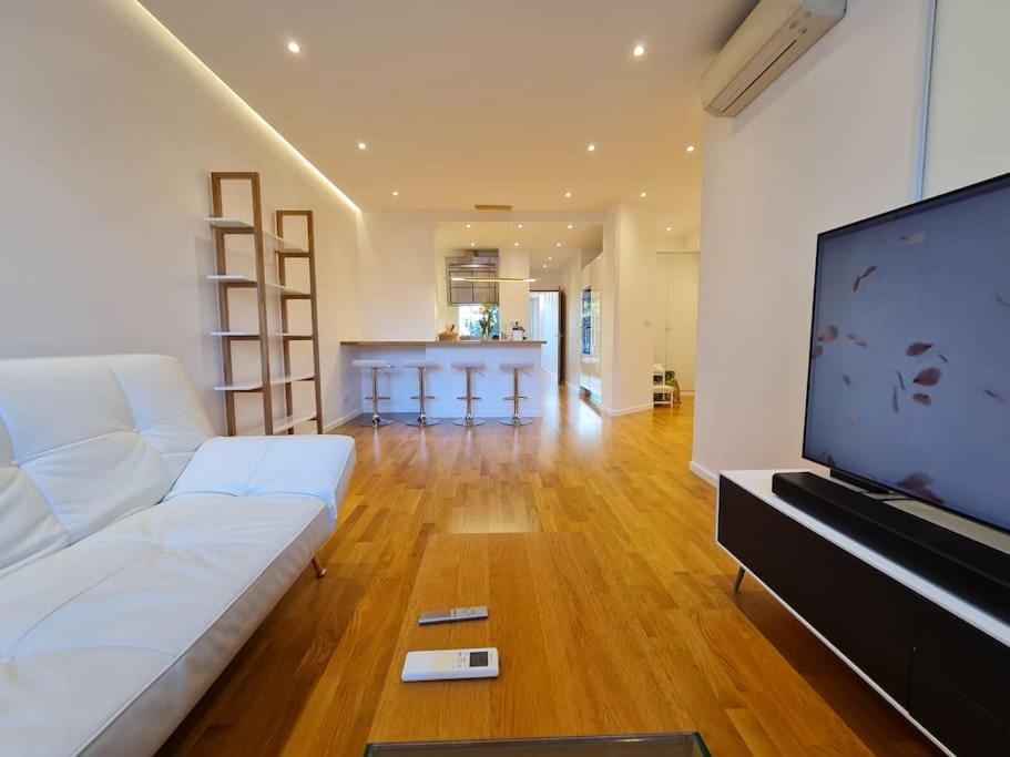 Il comprend un salon doté d'un canapé blanc et d'une télévision à écran plat. dans l'établissement Superbe 3 pièces rénové au cœur du Cap d'Antibes, à Antibes
