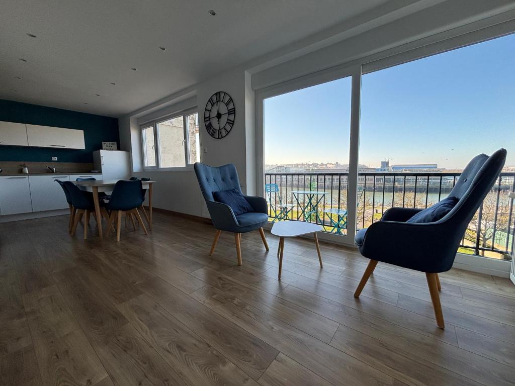 - un salon avec une table, des chaises et une horloge dans l'établissement T3 Nausicaa Parking gratuit, à Boulogne-sur-Mer