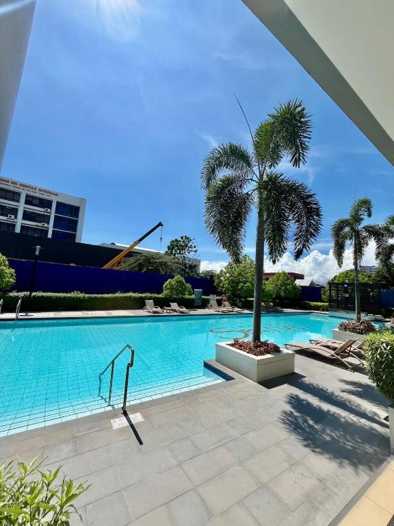 a swimming pool with a palm tree next to a building at Davao Downtown Condo With Pool Access in Davao City