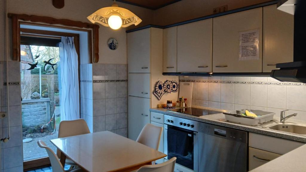 a kitchen with a table and a sink and a table and chairs at Nordseeferienhaus-Alma in Niebüll