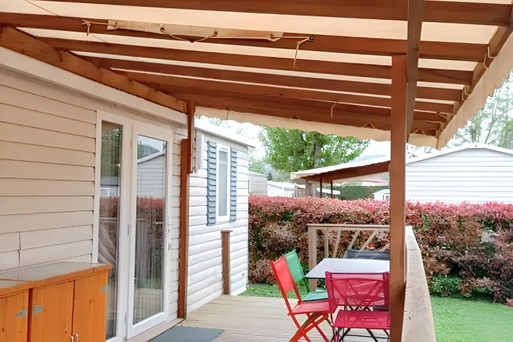 un patio avec une table et des chaises sous une pergola en bois dans l'établissement Bungalow confortable près de Condrieu avec piscine partagée, à Condrieu