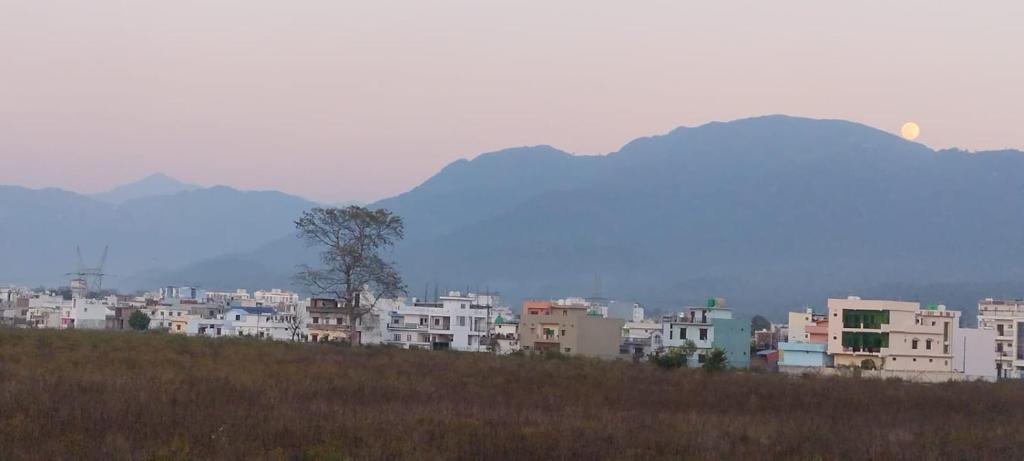 a group of buildings on a hill with mountains in the background at Zen Haven - Luxury Ganga Access & Mountain View in Rishīkesh