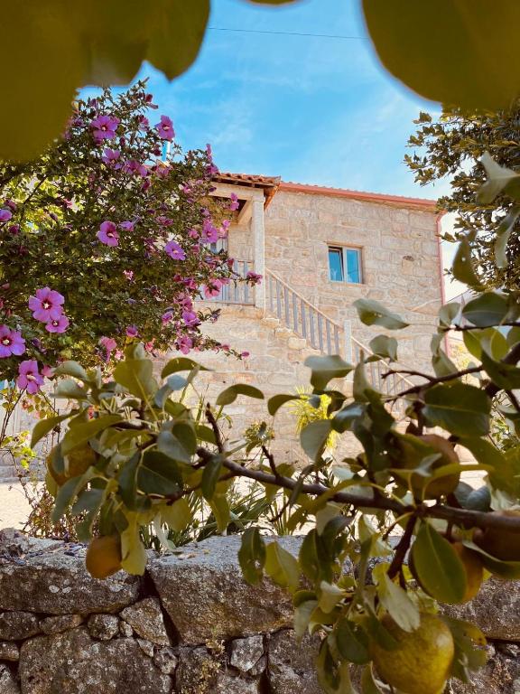 a stone building with pink flowers in front of it at Vila Adelaide in Campos