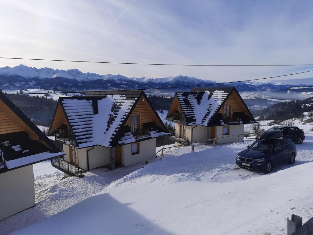 a row of houses in the snow with a car at Bajka w Gliczarowie in Bukowina Tatrzańska
