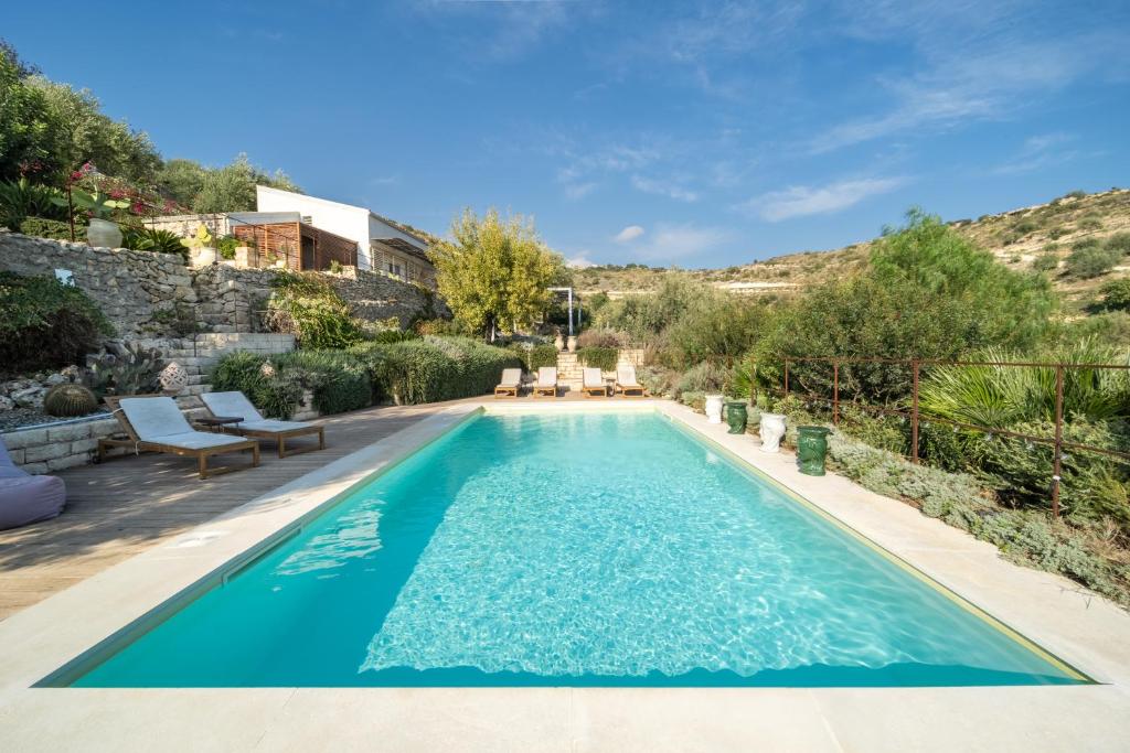 een zwembad met blauw water in een achtertuin bij Azalo Country House in Noto