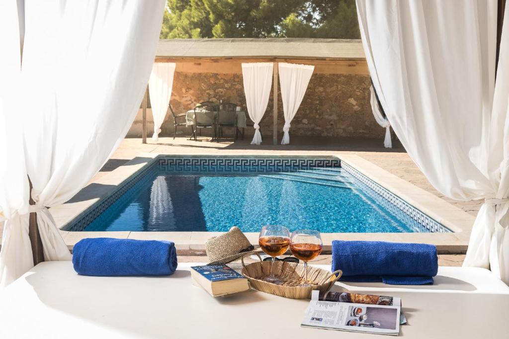 a table with wine glasses next to a swimming pool at Son Sea Villa in Campos
