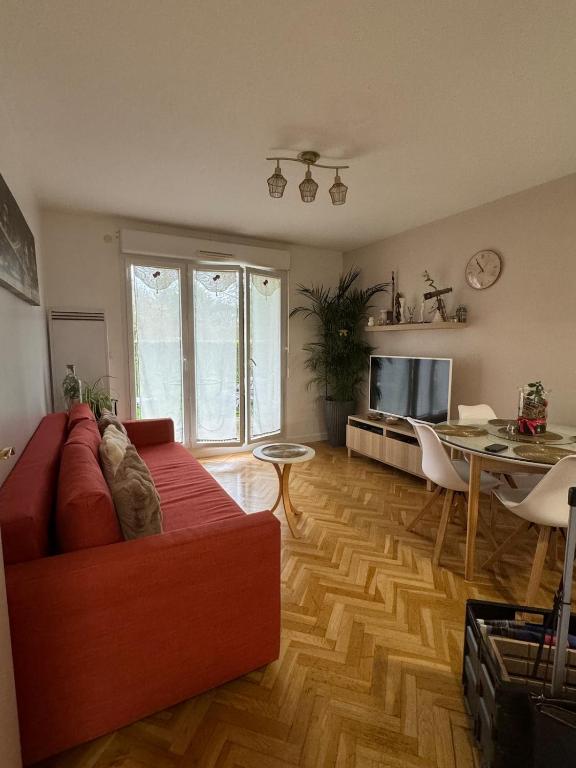 un salon avec un canapé rouge et une table dans l'établissement Appartement de vacance, à Montévrain